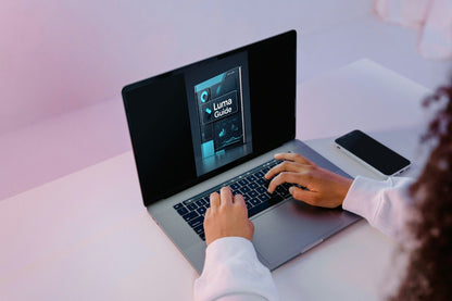 Person using a laptop with a screen displaying 'Luma Guide' on a light pink background